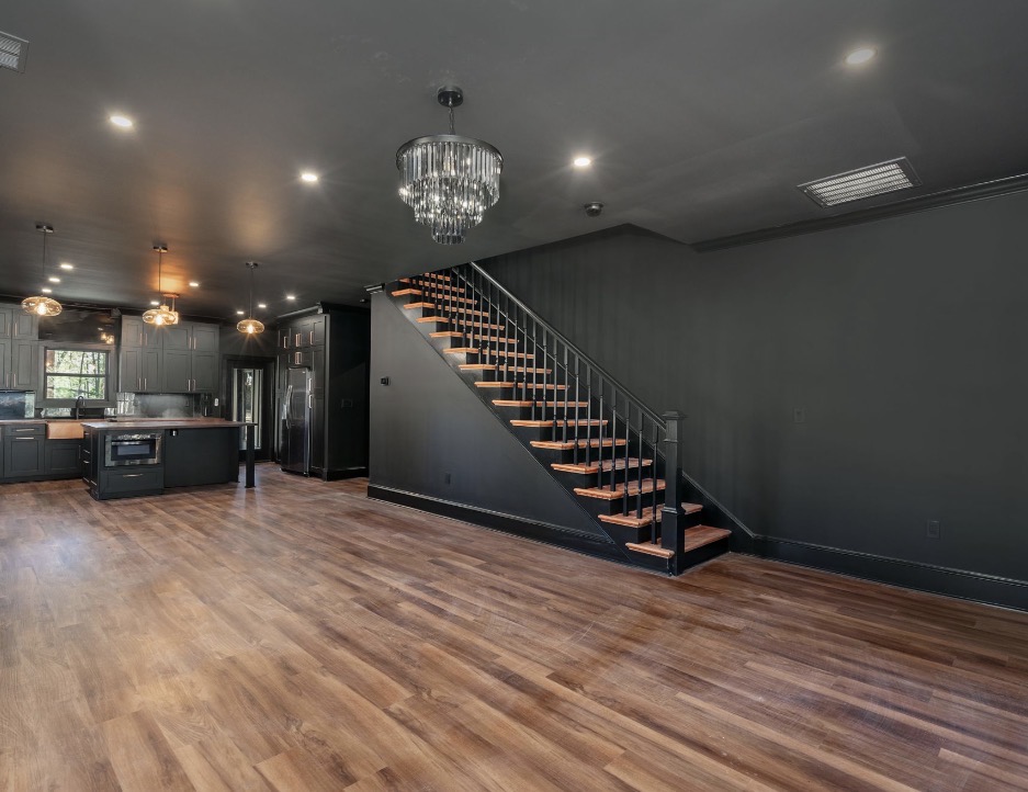 Living area with custom black staircase and view toward kitchen