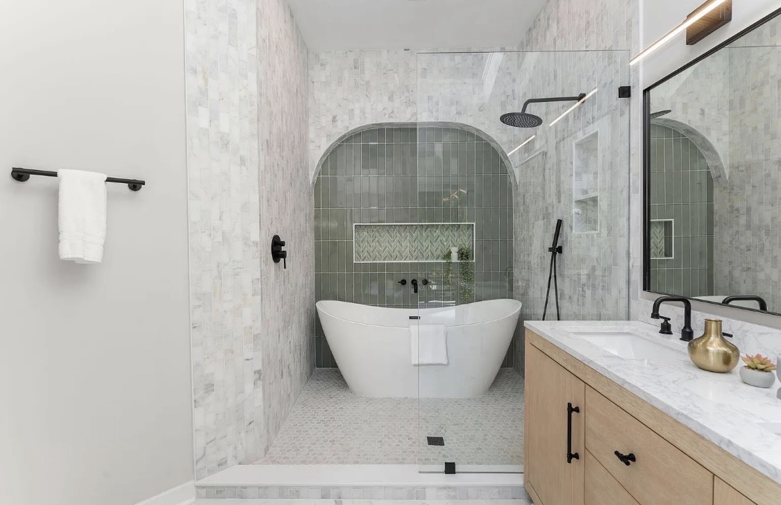 Primary bathroom wet room with sage-green arched tub alcove