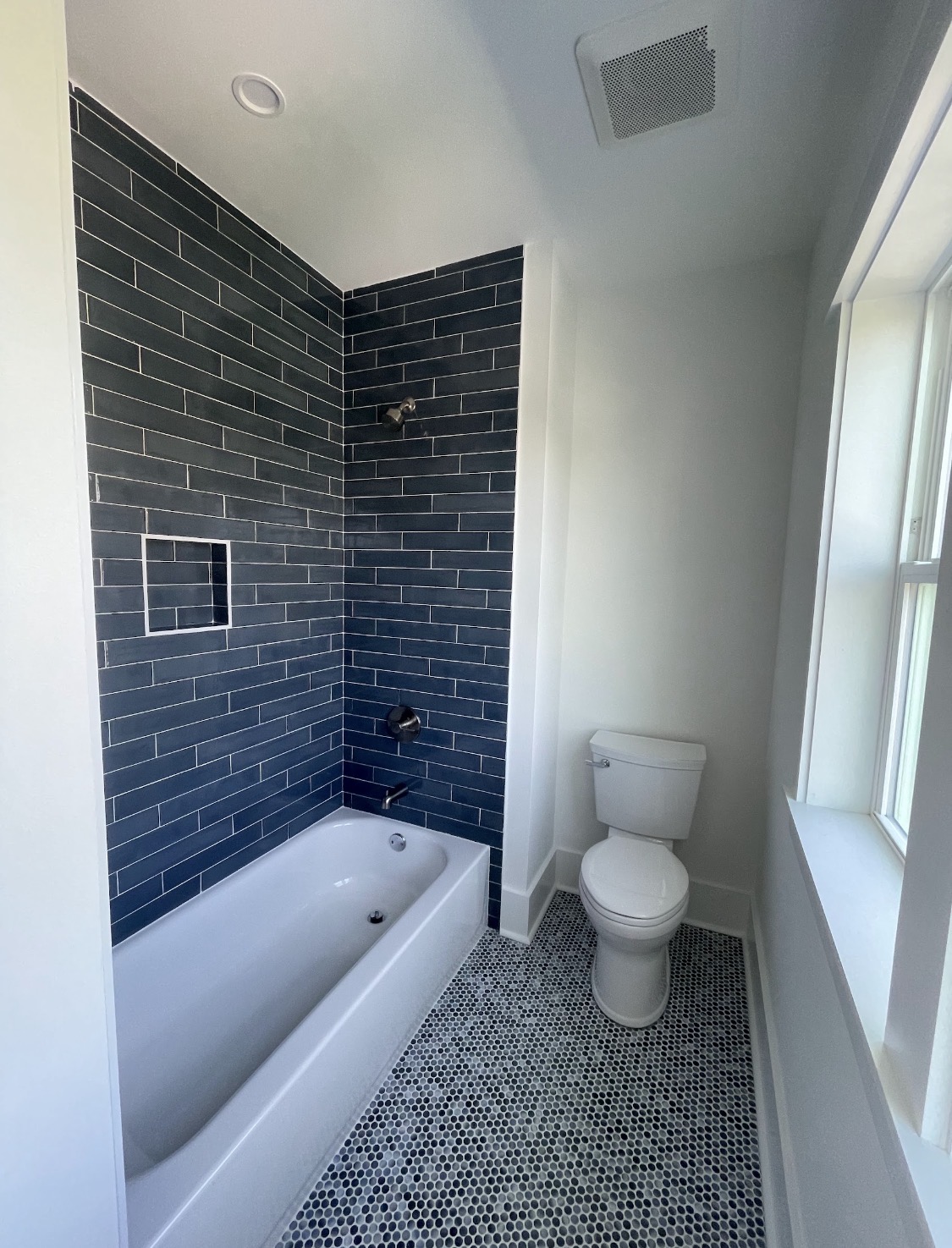 Bathtub and shower combo with blue-gray tile surround