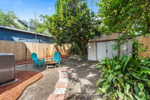 Landscaped backyard with teal Adirondack chairs and fire pit