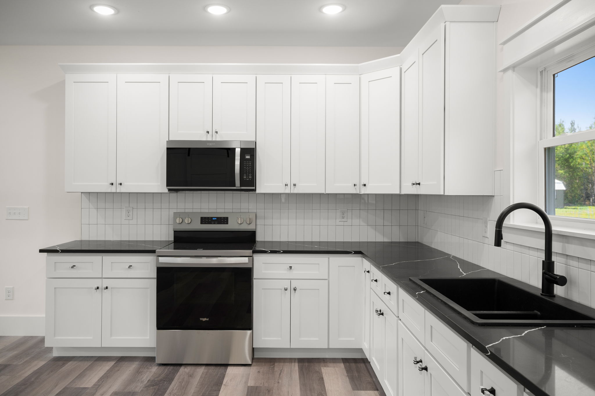 Kitchen corner with black quartz counters and Whirlpool range
