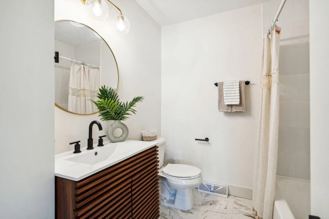 Hall bath with slatted wood vanity and gold mirror