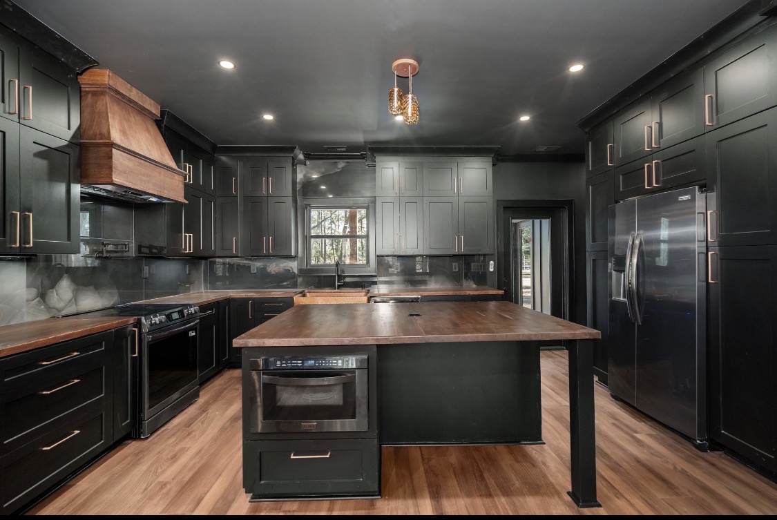 Kitchen with black cabinetry, copper hardware, and wood island