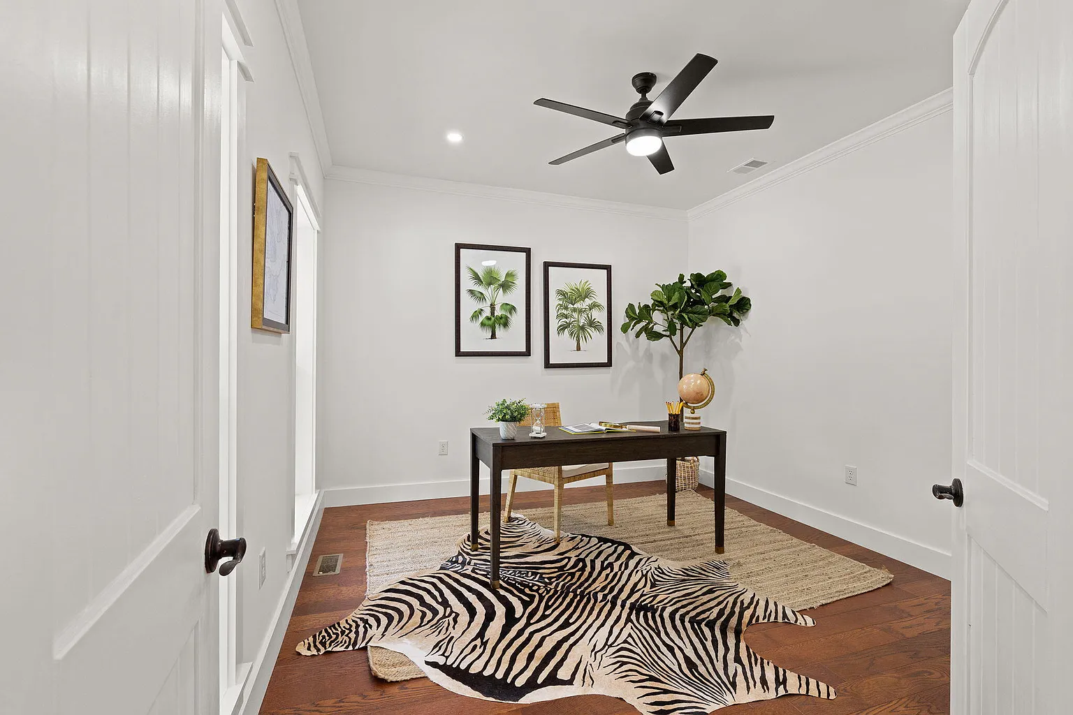 Home office with dark wood desk and botanical prints