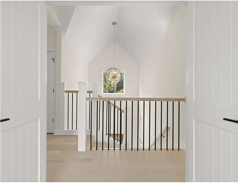 Upstairs landing with staircase railing and orb chandelier