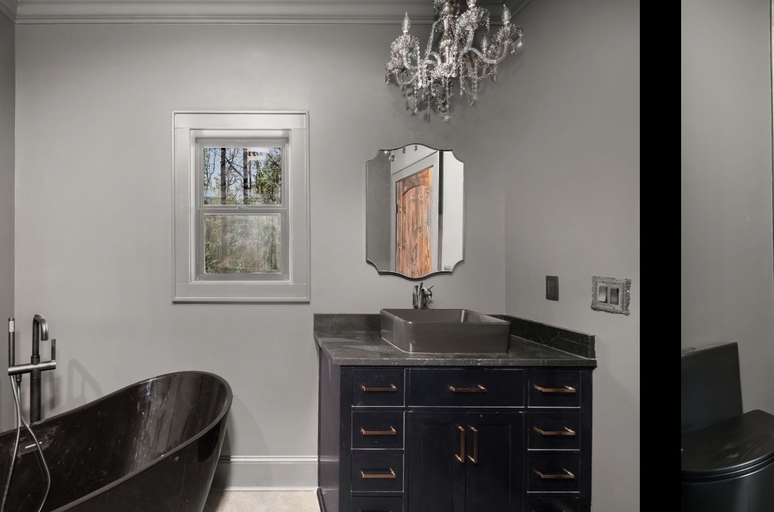 Bathroom with black soaking tub and copper hardware vanity
