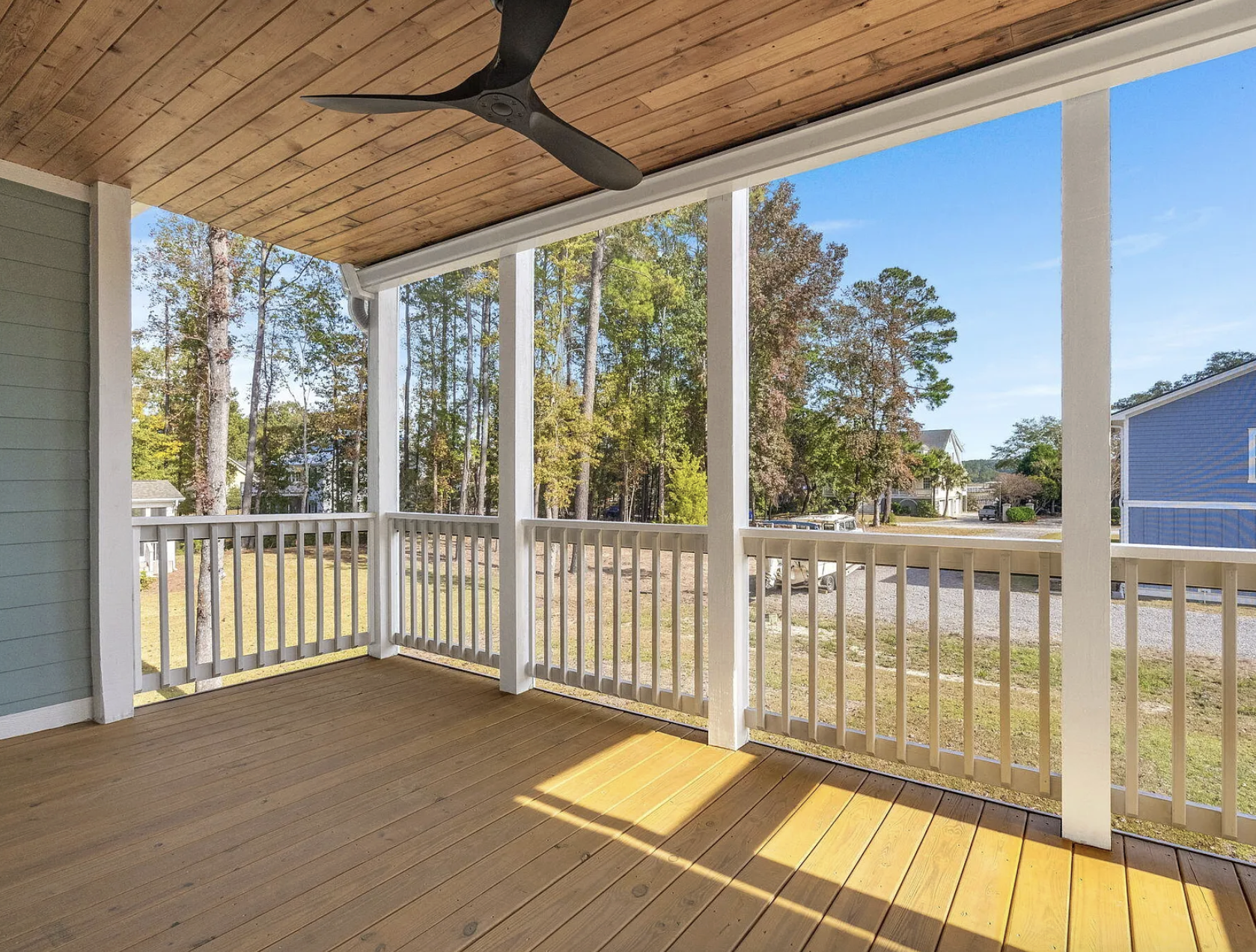 Porch with wood ceiling and white railing overlooking yard
