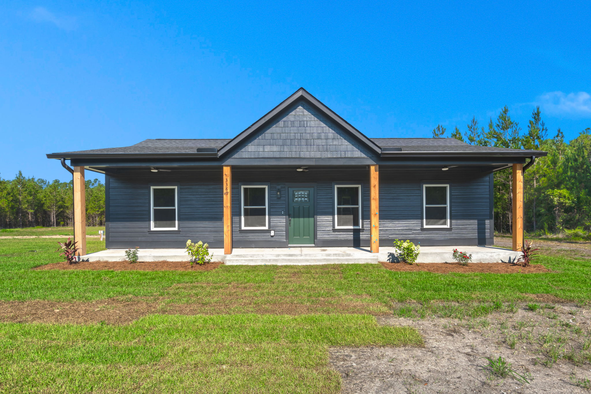 Dark-charcoal farmhouse front with wood porch posts and green door