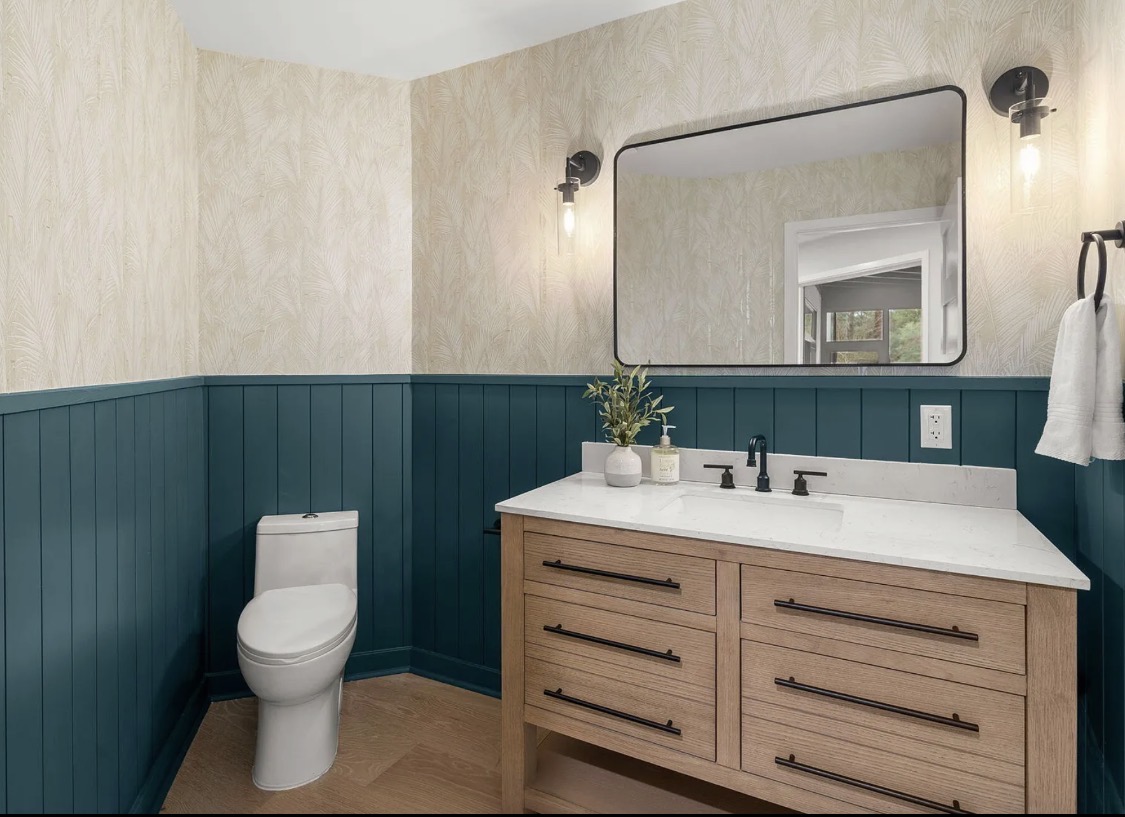 Bathroom with teal wainscoting and botanical wallpaper