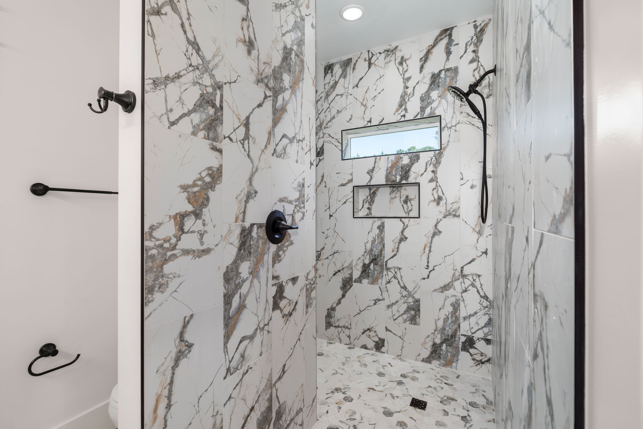 Walk-in shower with marble-look tile and matte black fixtures