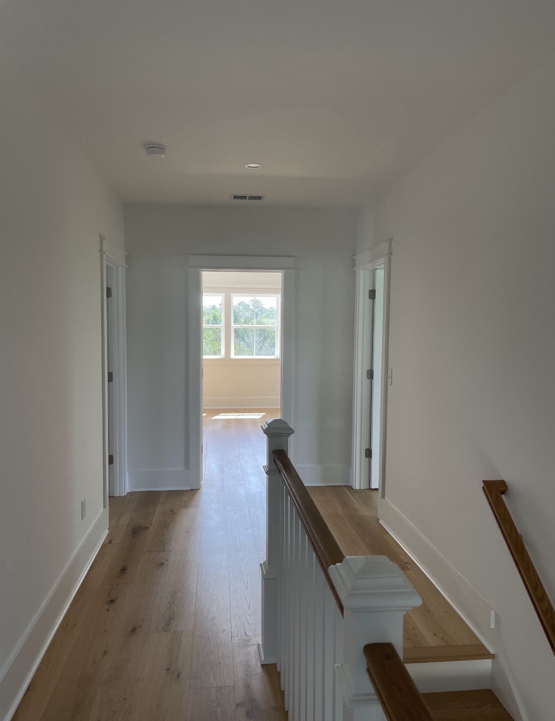 Hallway with oak floors and white spindle staircase railing