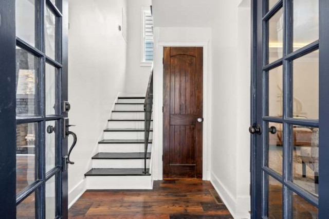 Entry hallway with navy glass doors and dark-stained stairs