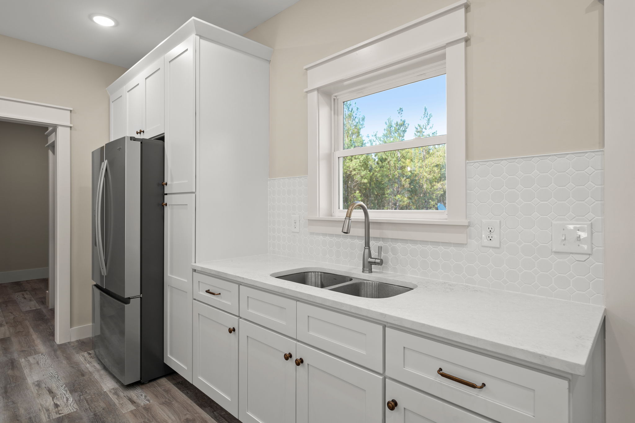 Sink station with hexagon tile, stainless basin, and window views