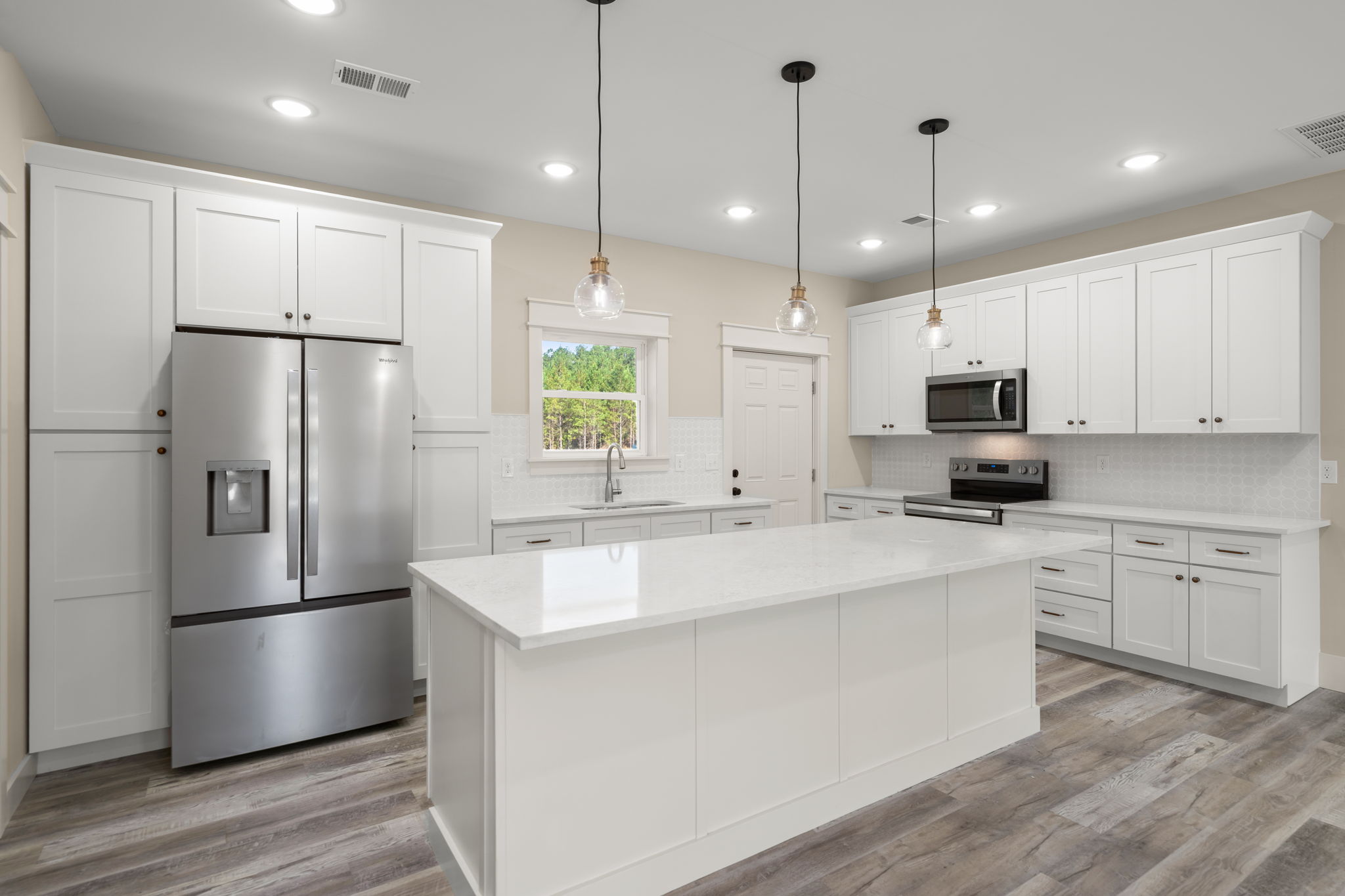 Kitchen with white quartz island and pendant lights over stainless range