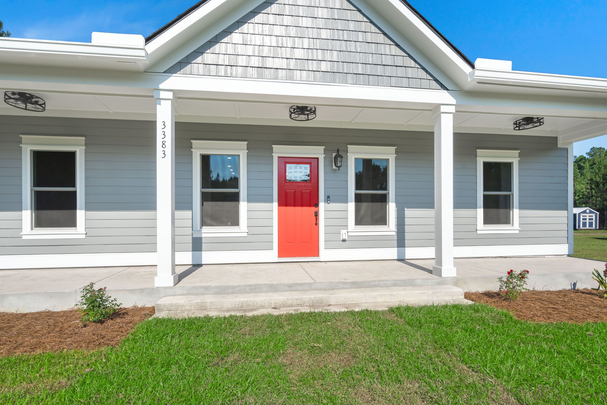 Covered porch with caged pendant lights and red front door