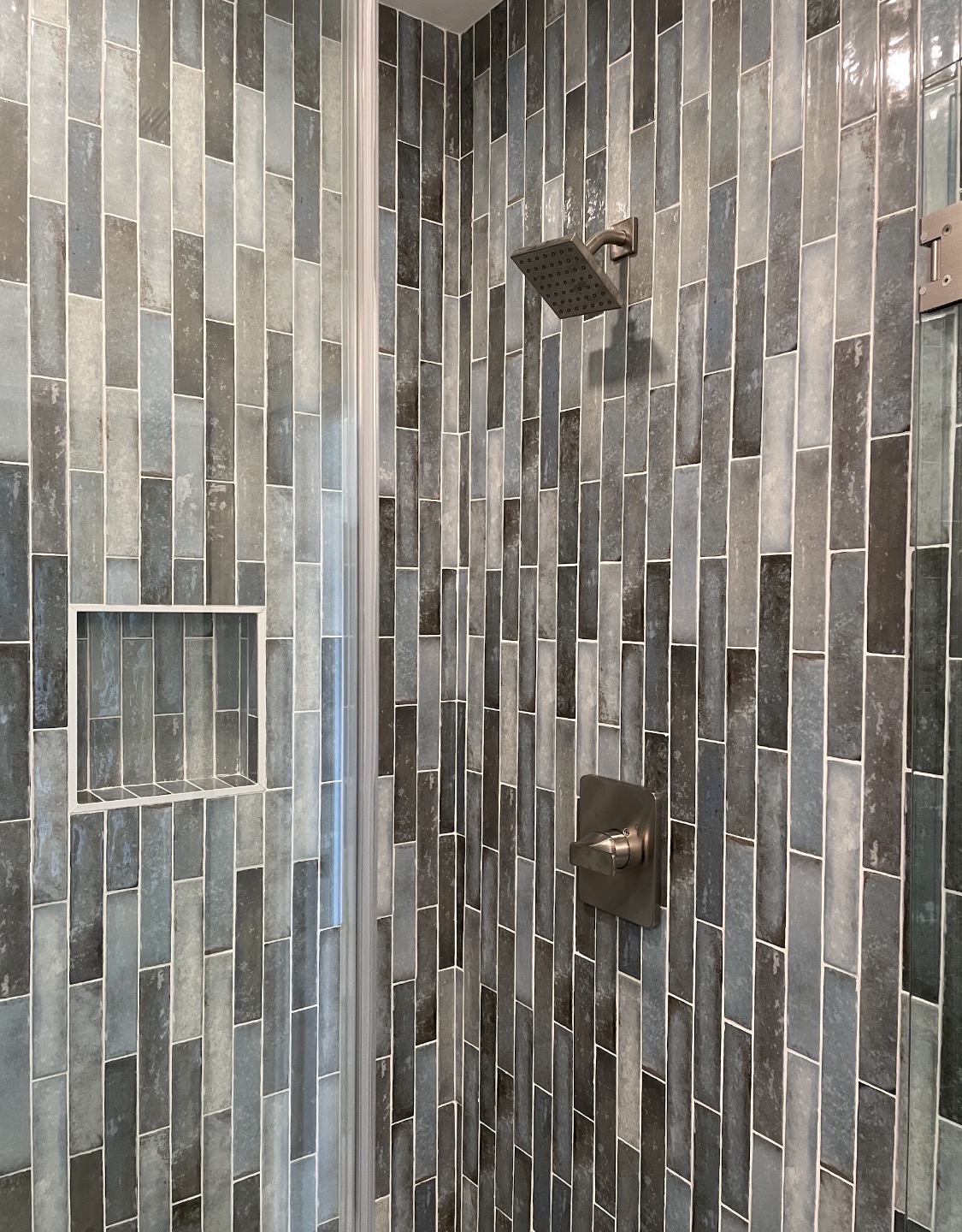 Shower interior with vertical slate-blue tile and recessed niche