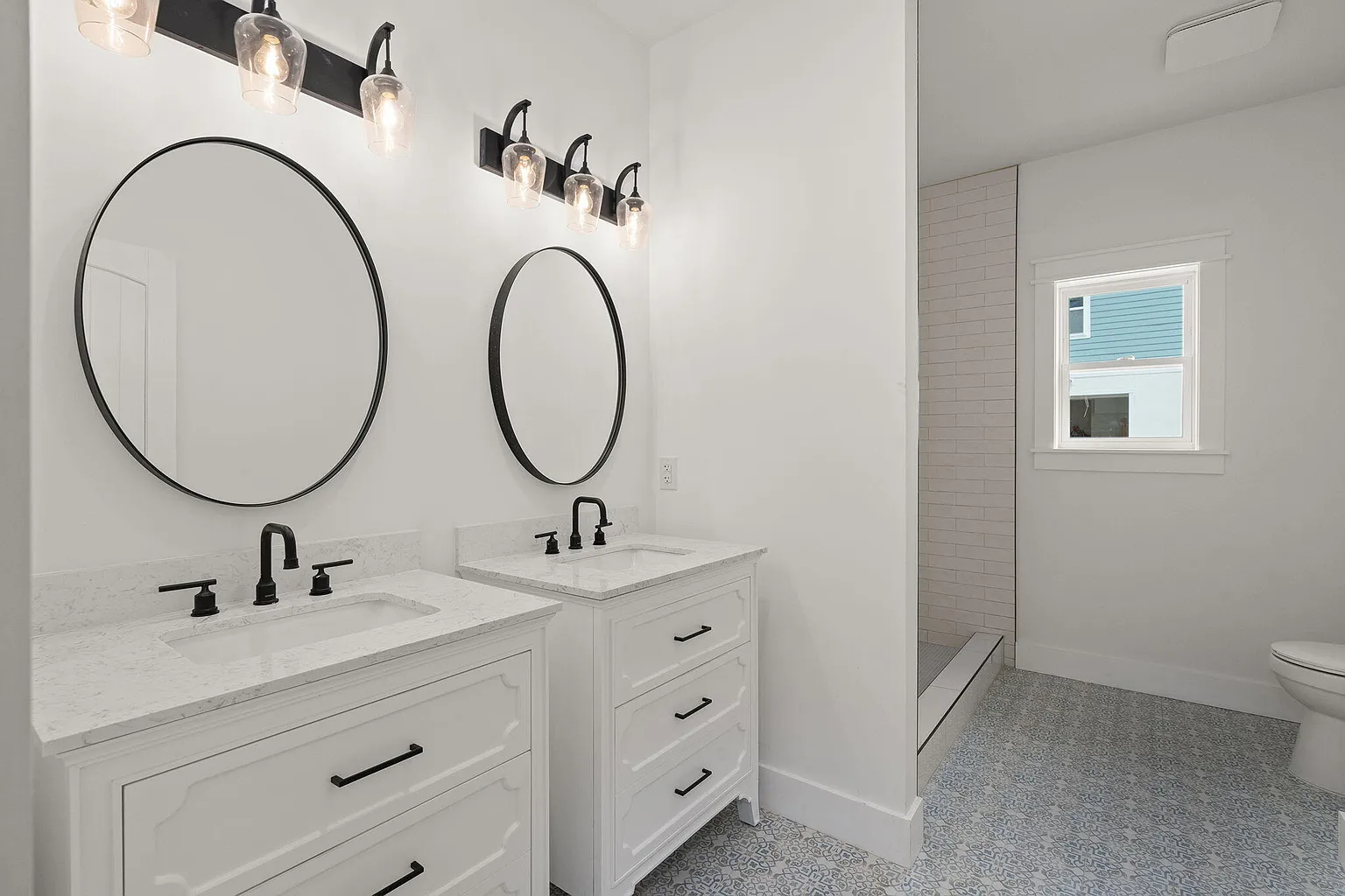 Double vanity with black-framed mirrors and patterned floor tile