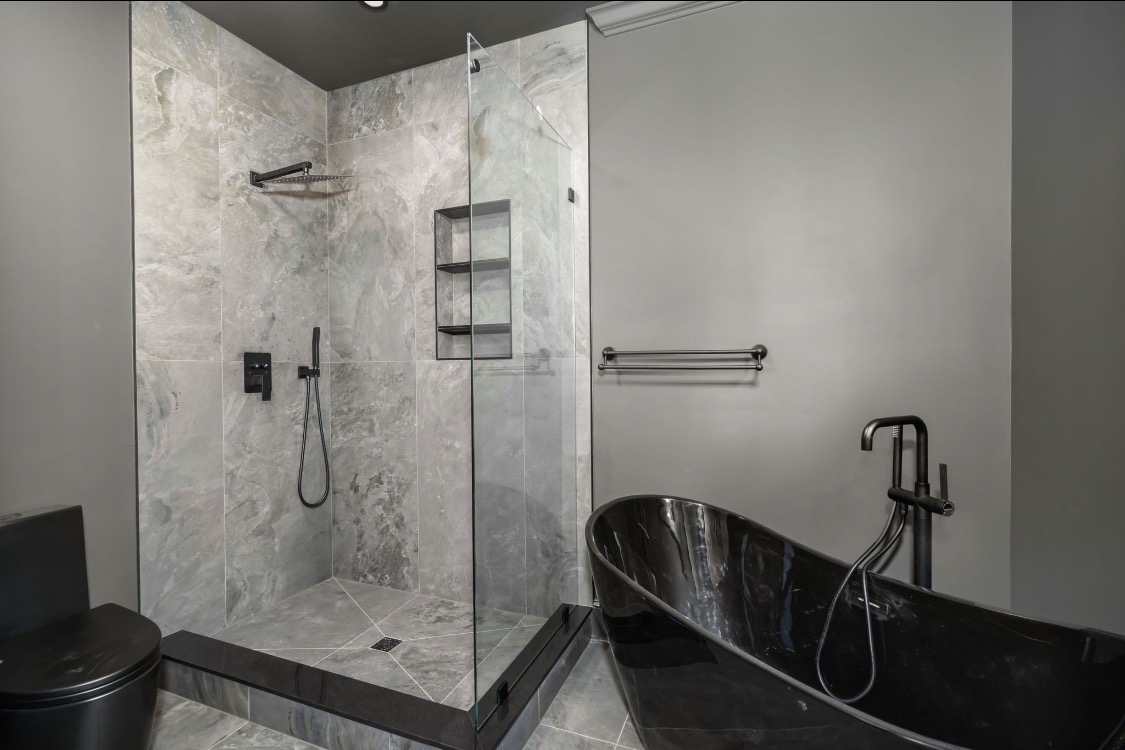 Bathroom with black freestanding tub and marble shower