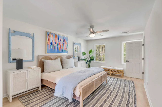 Primary bedroom with cane headboard and blue-framed mirrors