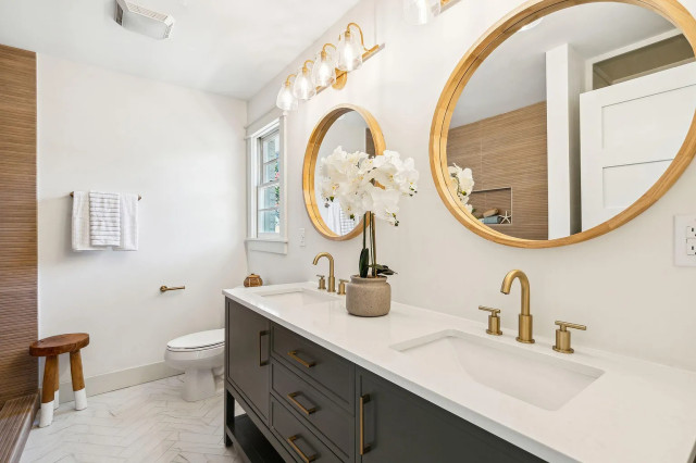 Primary bath double vanity with brass globes and herringbone floor