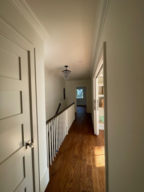 Upstairs hallway with crystal chandelier and staircase