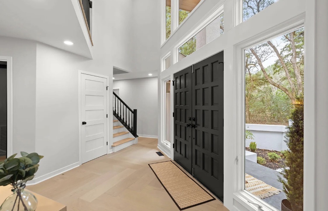 Vaulted entryway with black double doors and oak staircase