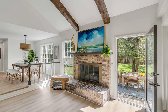 Vaulted living room with brick fireplace and open French doors