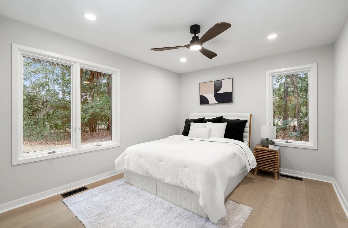 Primary bedroom with upholstered headboard and chevron floors