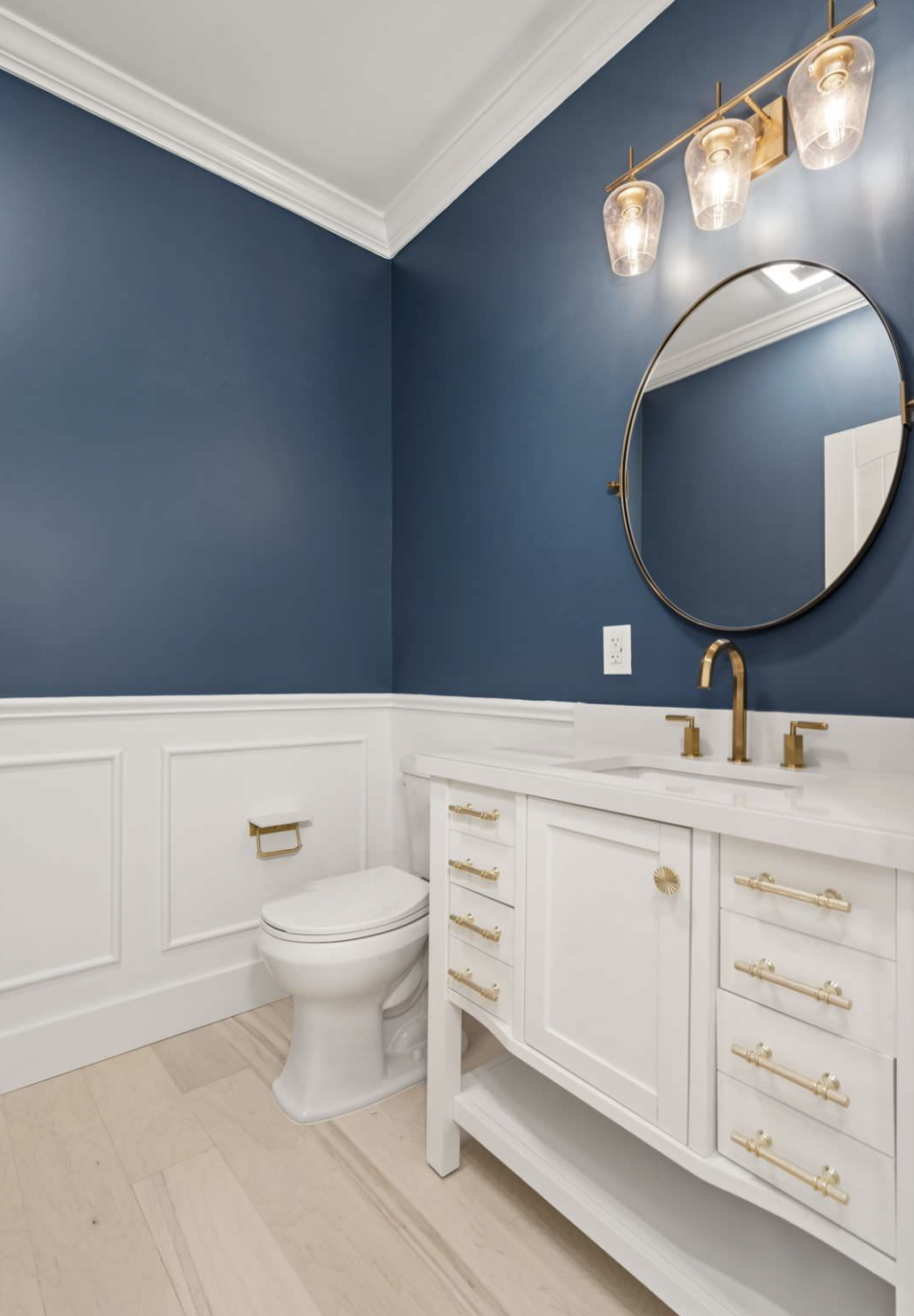 Powder room with navy walls and brass vanity