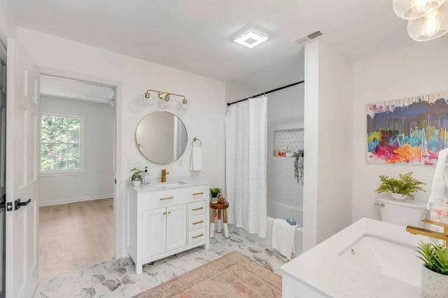White vanity bathroom with brass fixtures and hexagon floor tile