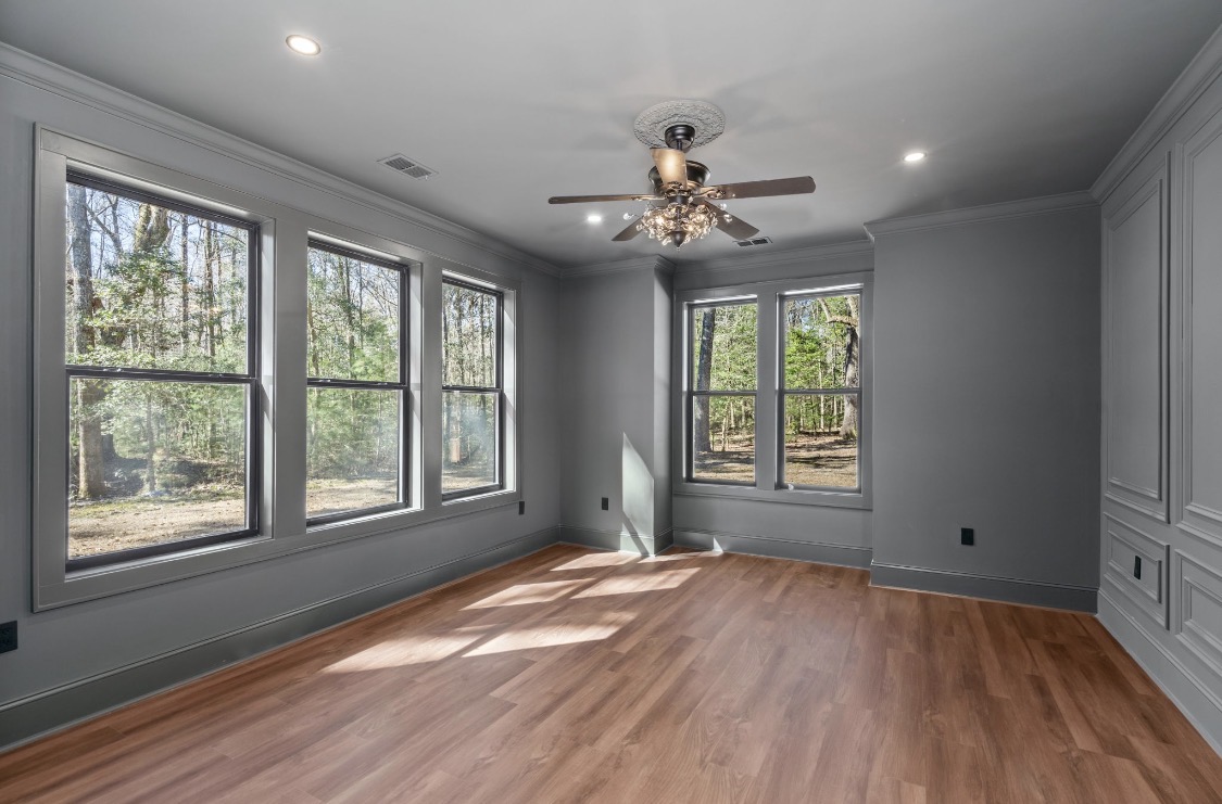 Grey room with recessed millwork paneling and triple windows