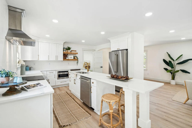 White kitchen island with rattan bar stools and floating shelves