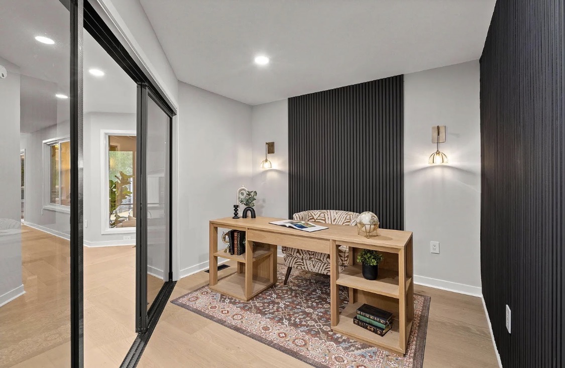 Home office with black slat accent wall and gold sconces