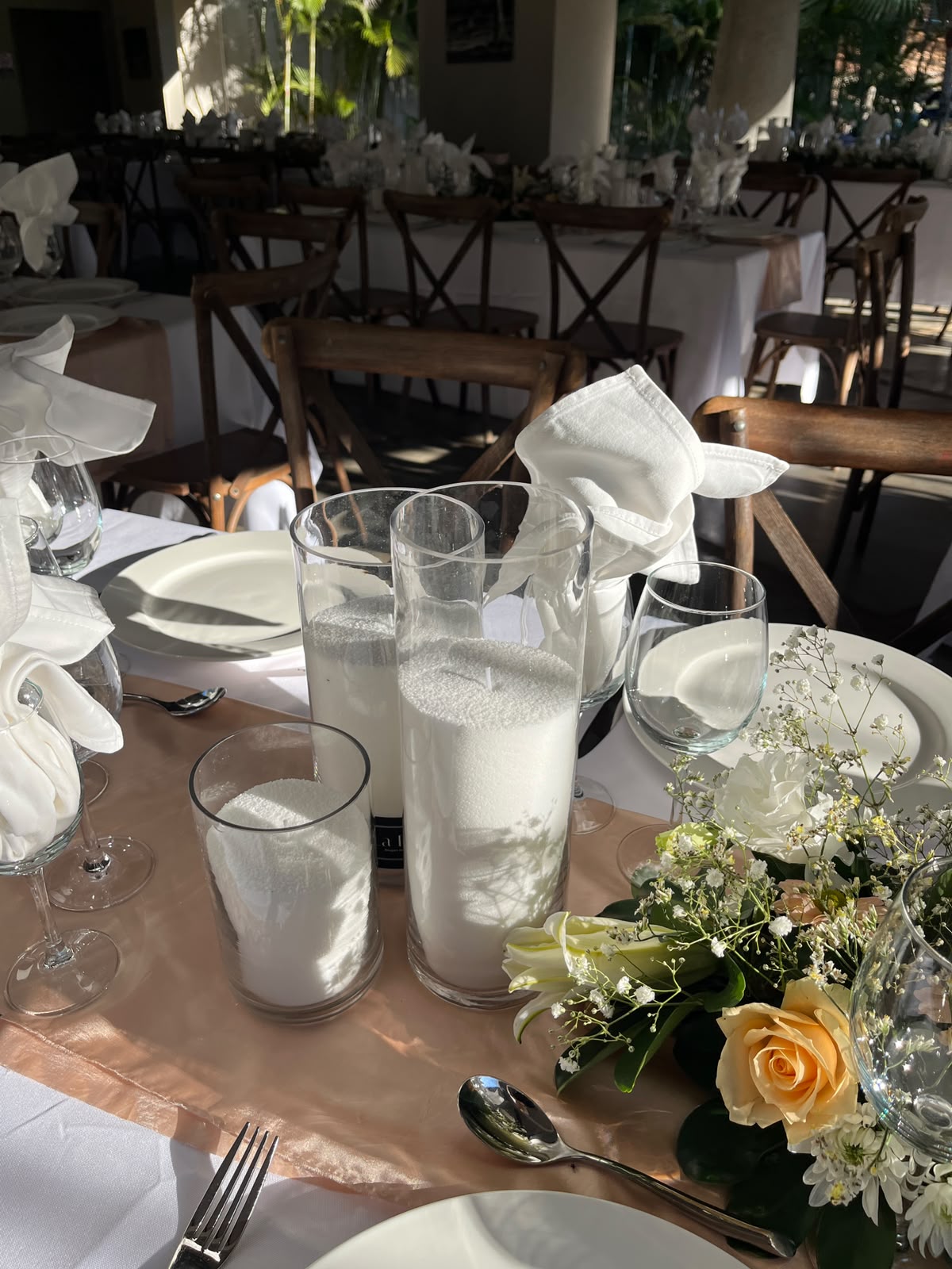 Centre de table avec roses pêche et photophores sur runner champagne