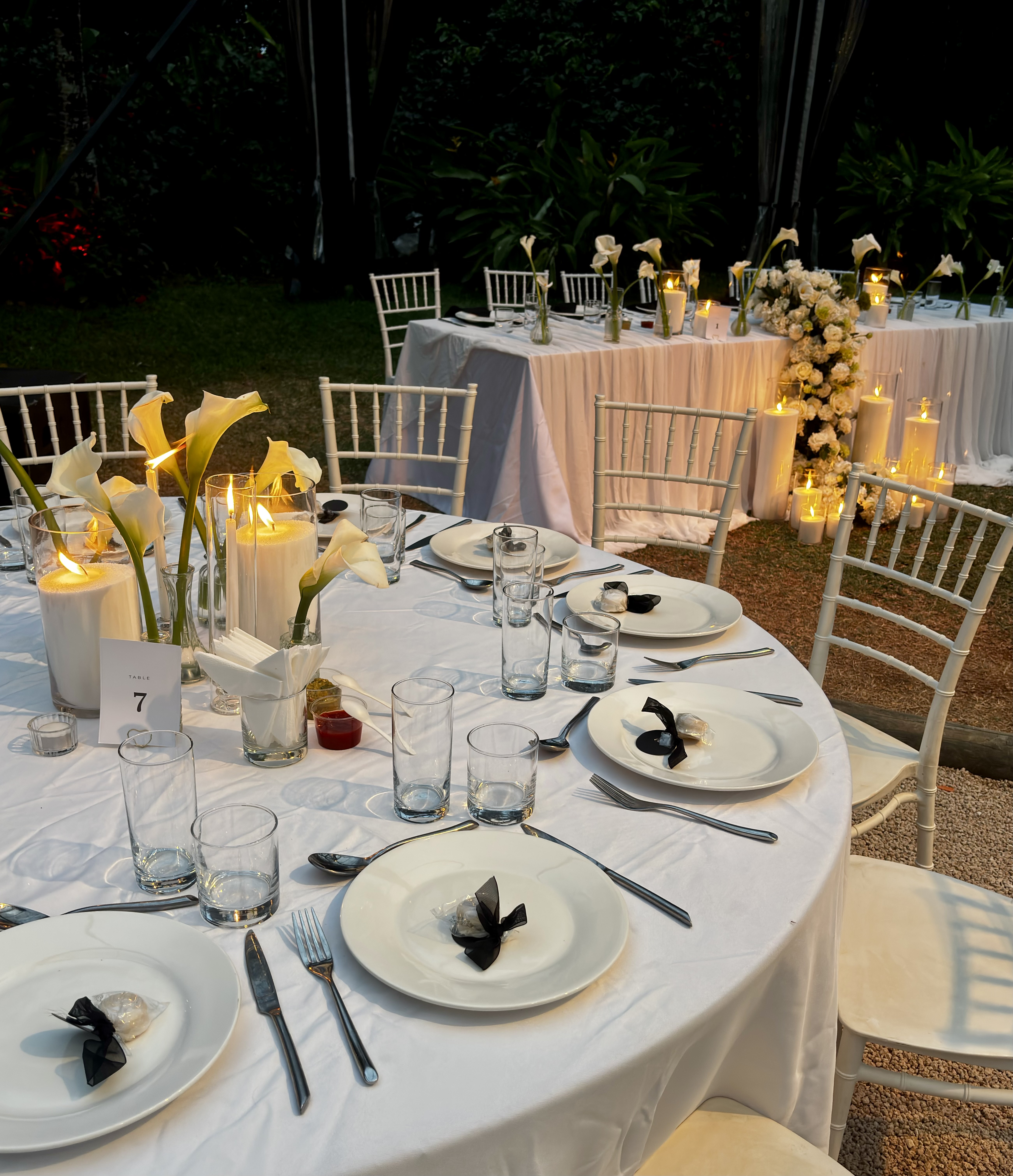 Table dressée avec photophores, callas et marque-place pour réception de mariage