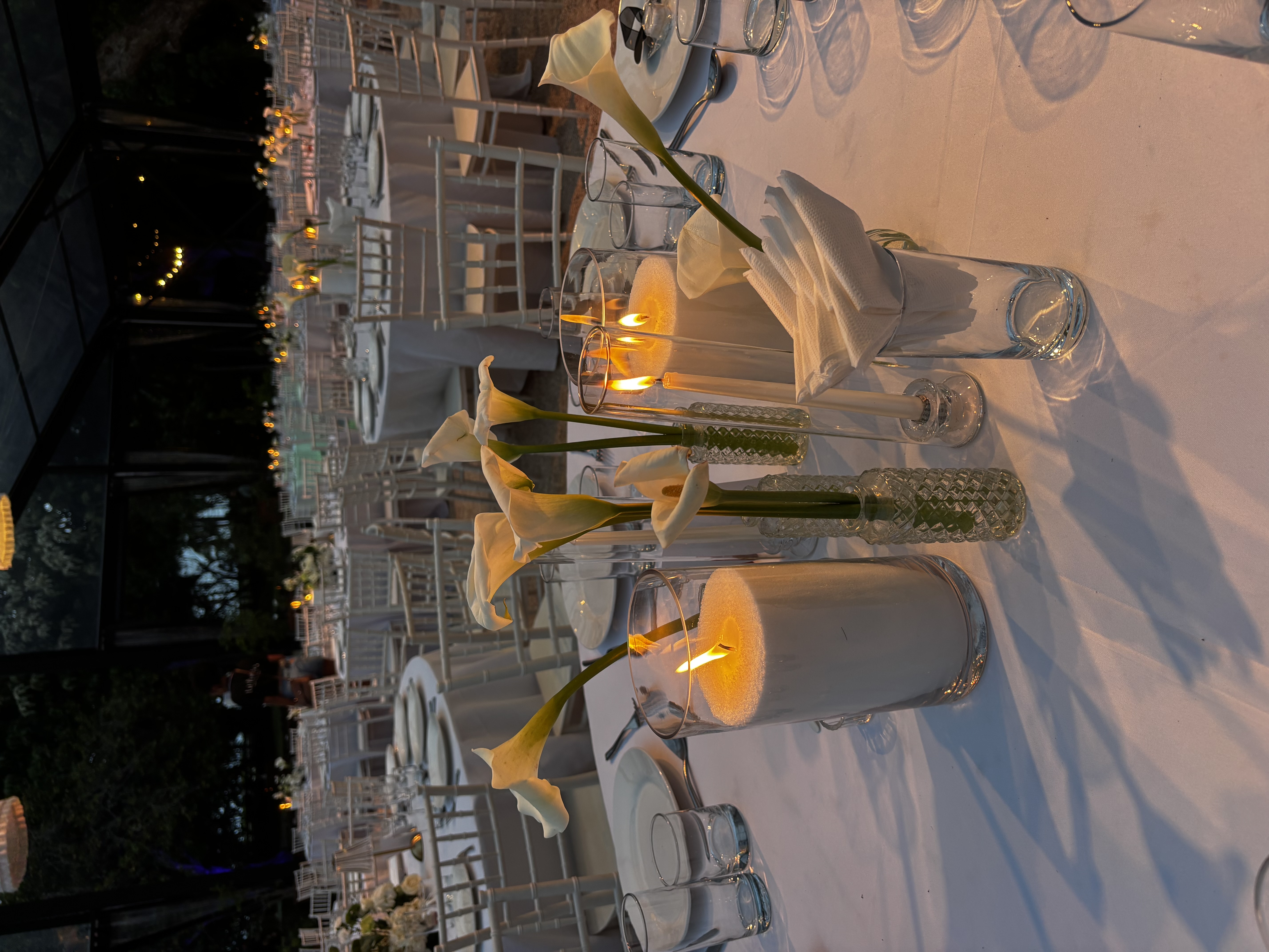 Centre de table avec callas blanches et photophores cylindriques sur table de réception