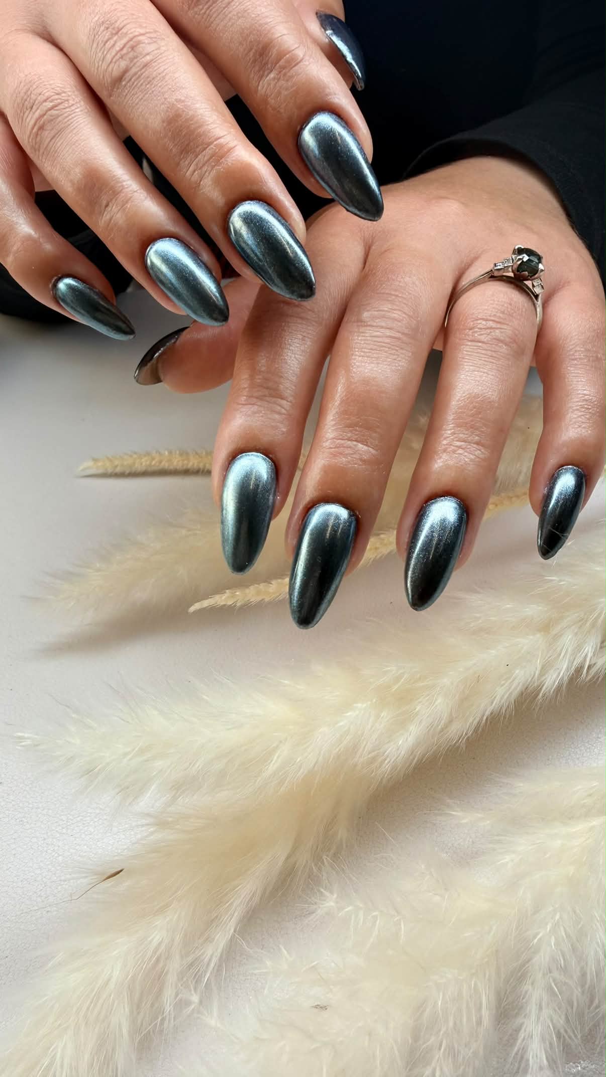 Metallic teal almond nails with luminous cat-eye highlights