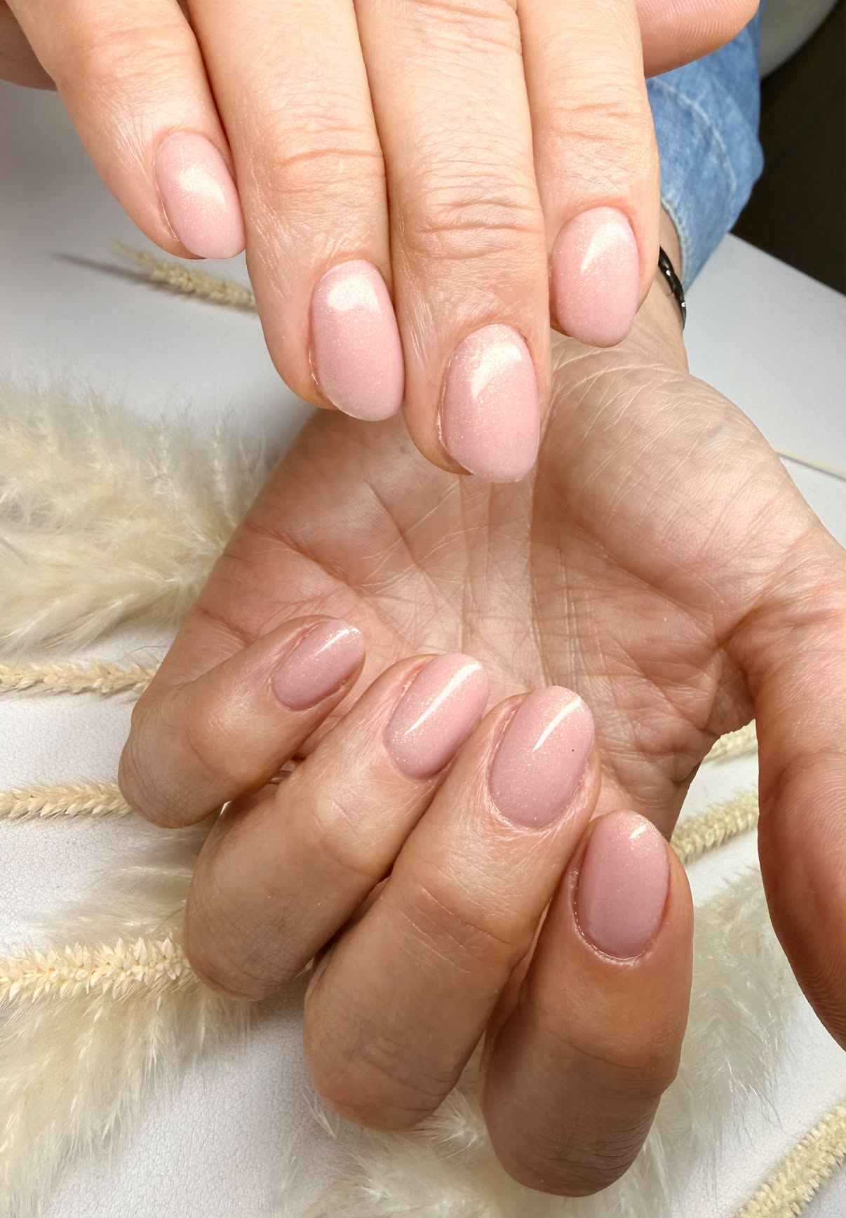 Short rounded nails with pale pink shimmer polish