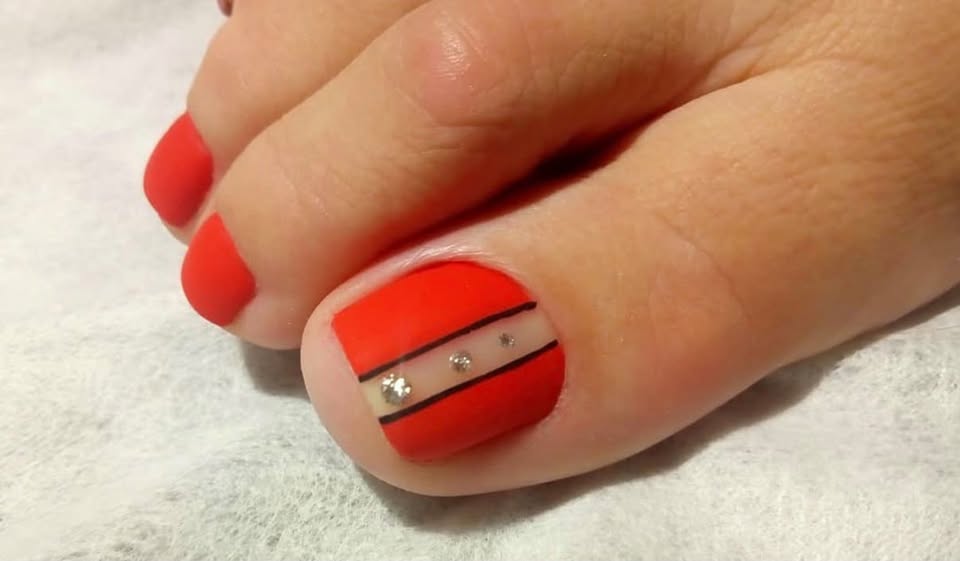 Red toenails with a striped accent and decorative details