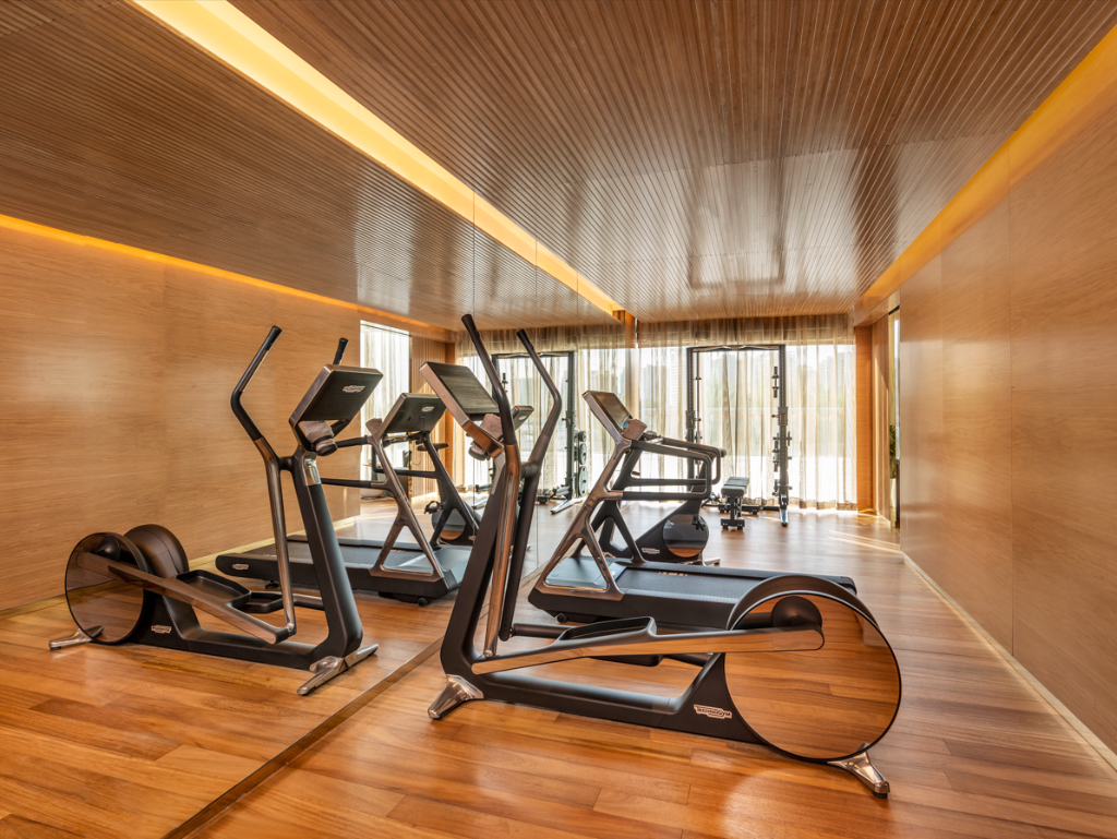 Private luxury home gym Qatar villa - warm wood paneling Technogym equipment The Pearl Doha