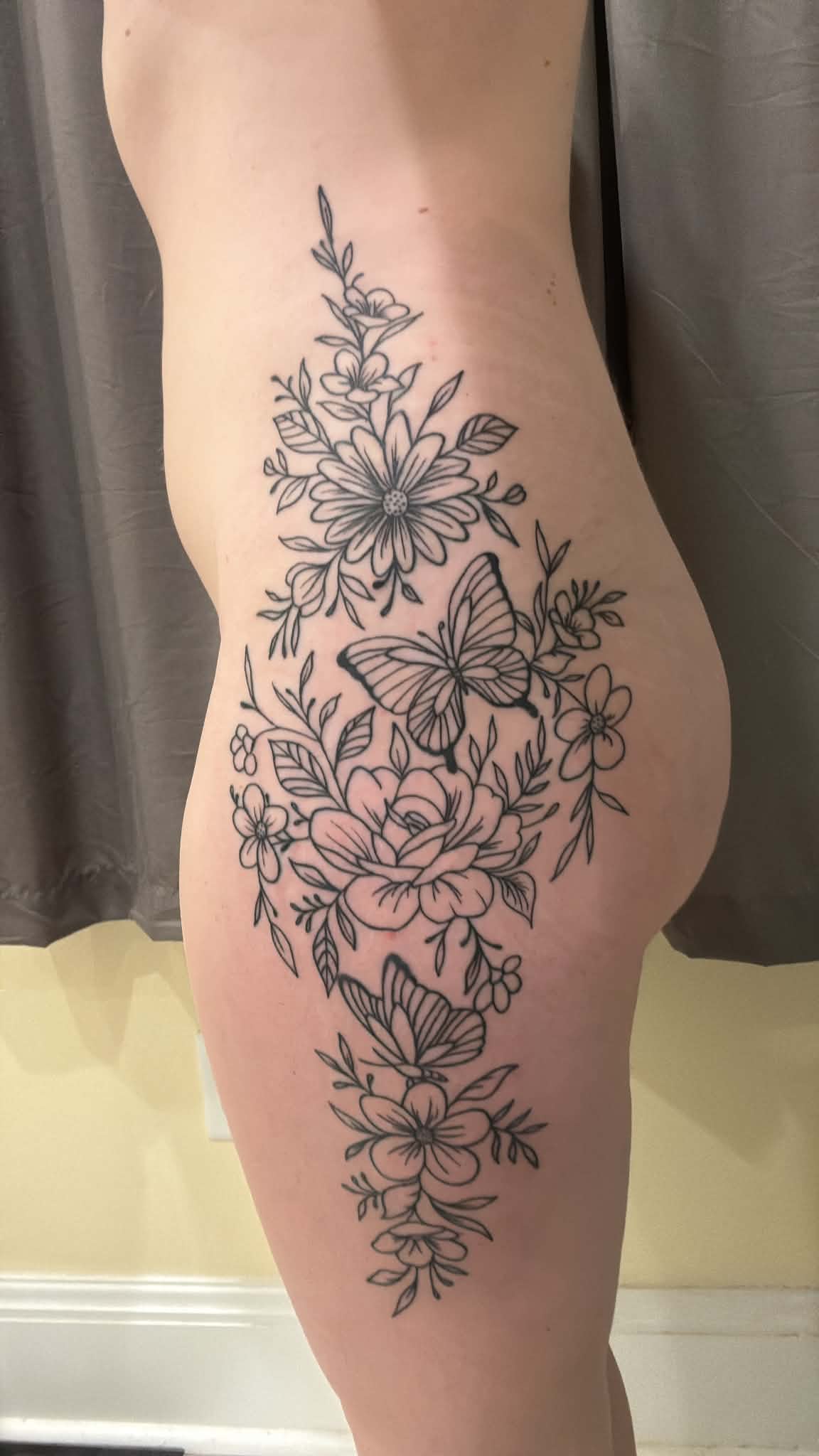 One side of the full body floral and butterfly fine line tattoo