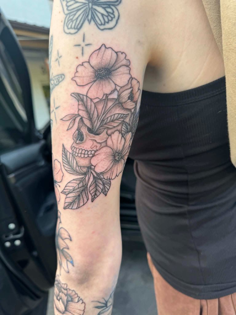 Skull with flowers arm tattoo