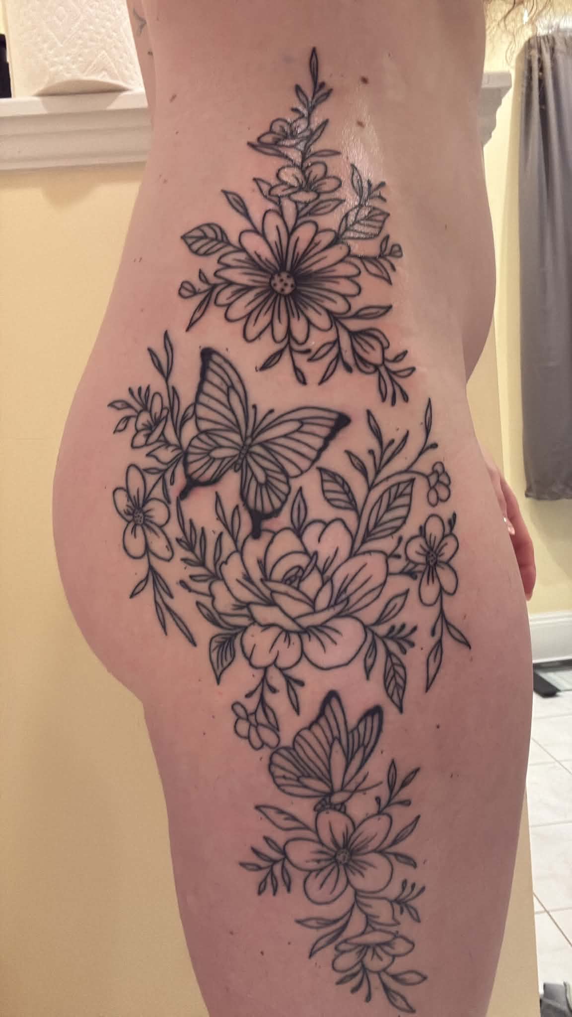 Opposite side of the full body floral and butterfly fine line tattoo