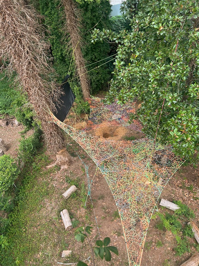 Tensioned fiber art installation suspended between trees