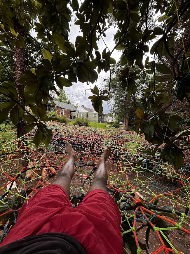 Reclining in a neon green and orange net under the canopy