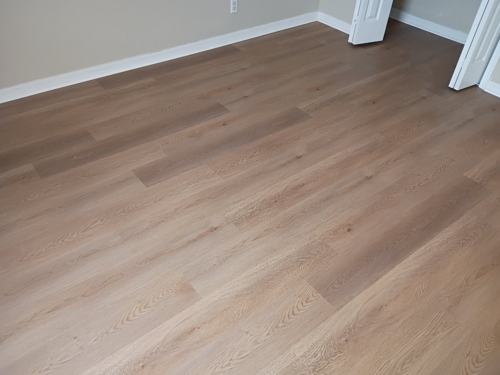 Residential bedroom installation showing seamless flow and natural wood grain of Wismar Oak luxury vinyl planks
