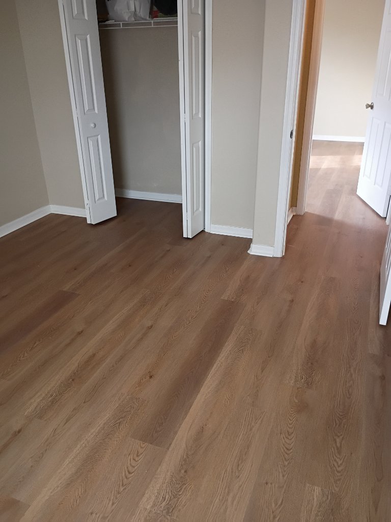 Residential waterproof vinyl plank flooring installation in master bedroom with natural oak grain appearance