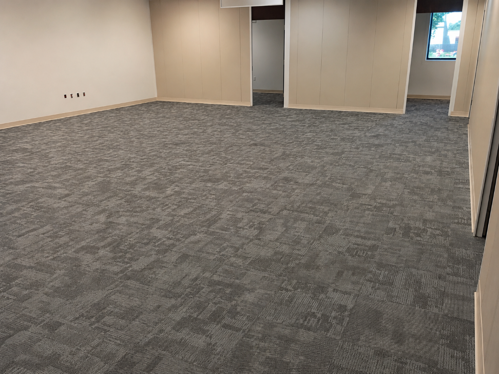 Worn carpet tile replaced with new modular carpet tile in a staggered ashlar pattern.
