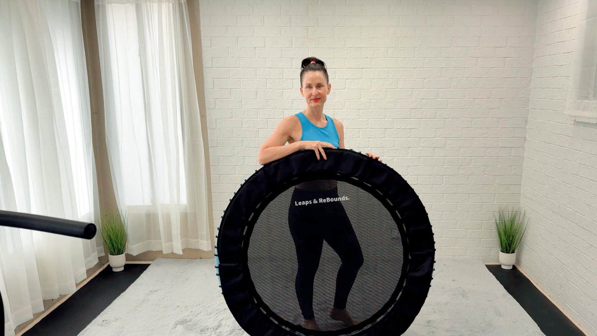 Angie holding a rebounder in her workout studio