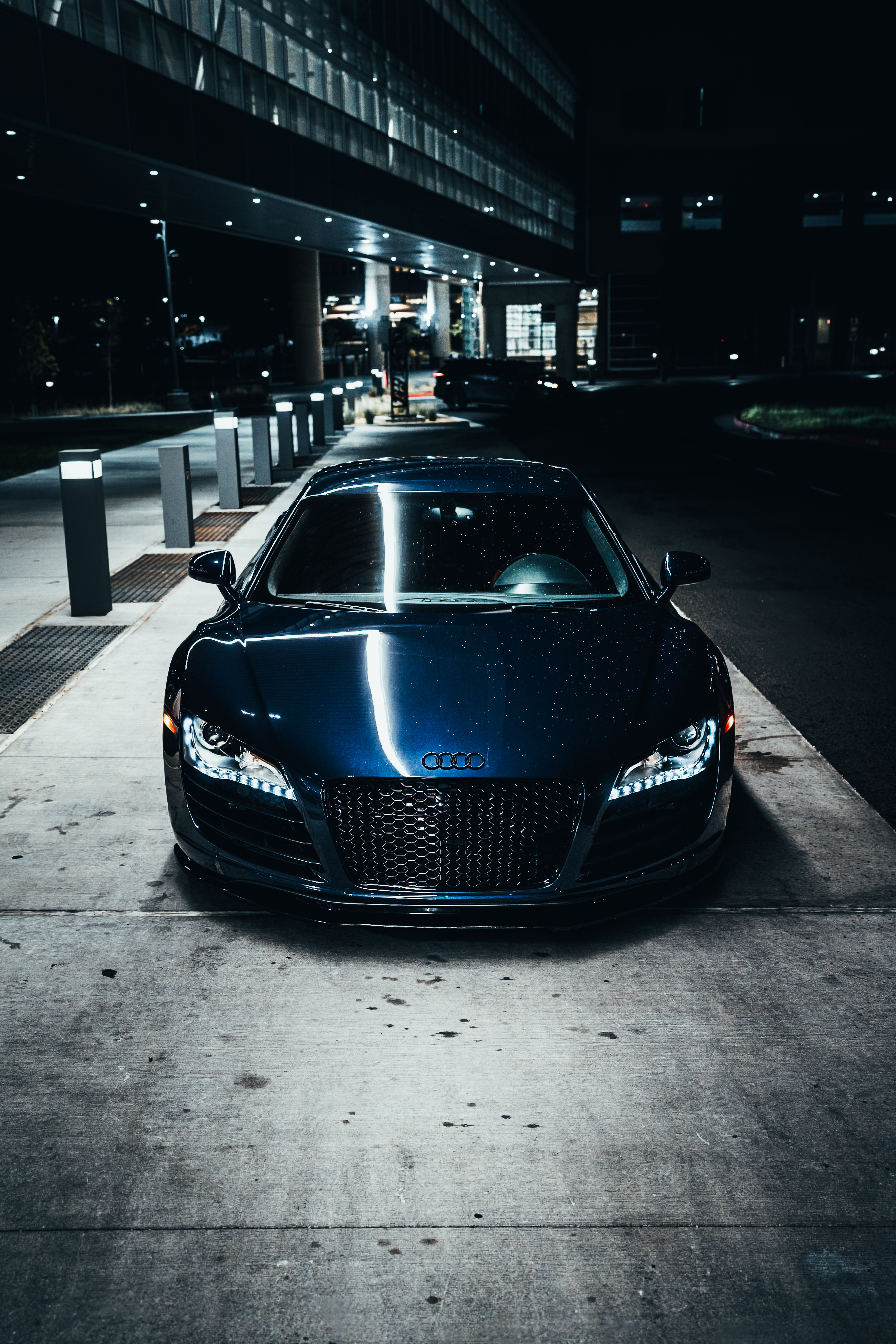 Audi R8 Night Shoot - photography automotive photography by Chan2blazed Media: A dark metallic blue Audi R8 captured under modern architectural lighting at night — high-contrast reflections and moody atmosphere.